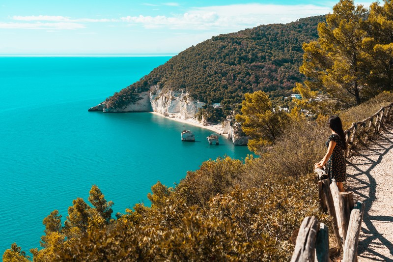 Baia delle Zagare: Eine Frau blickt vom Wanderweg auf die Küste der Baia delle Zagare in Apulien