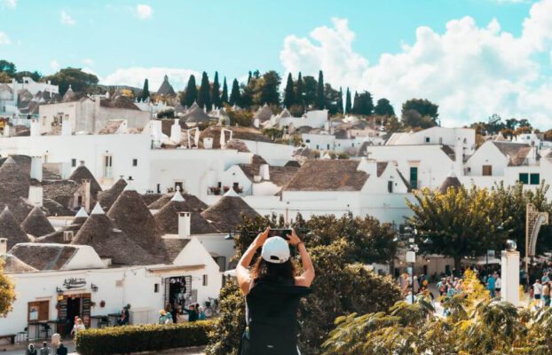 Eine Touristen freut sich über die vielen Alberobello Sehenswürdigkeiten und macht Fotos