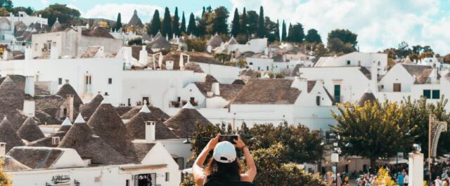 Eine Touristen freut sich über die vielen Alberobello Sehenswürdigkeiten und macht Fotos