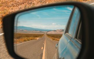 Straße im Rückspiegel auf einem Roadtrip. Im Hintergrund laufen die besten Roadtrip Songs