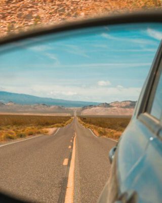 Straße im Rückspiegel auf einem Roadtrip. Im Hintergrund laufen die besten Roadtrip Songs