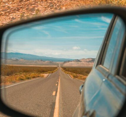 Straße im Rückspiegel auf einem Roadtrip. Im Hintergrund laufen die besten Roadtrip Songs