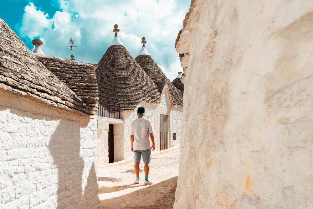 Mann läuftz durch eine leere Gasse mit Trulli in Alberobello