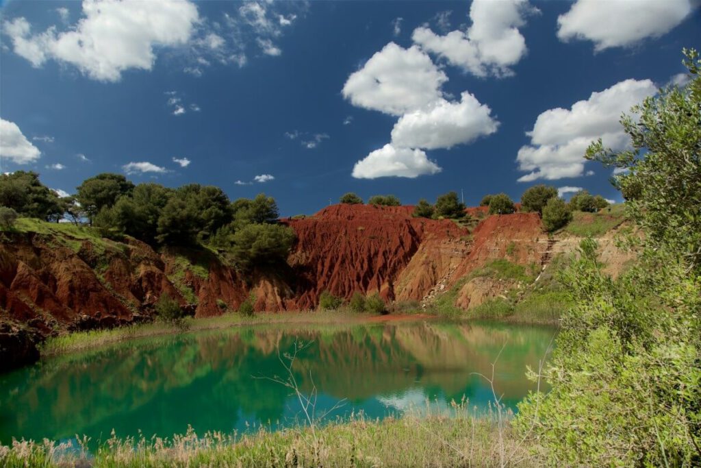 Der See und die rostbraunen Berge der Cava di Bauxite