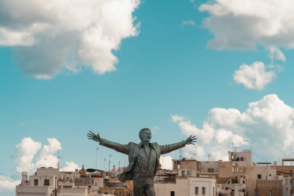 Domenico Modugno Statue mit Dächern von Polignano a Mare im Hintergrund