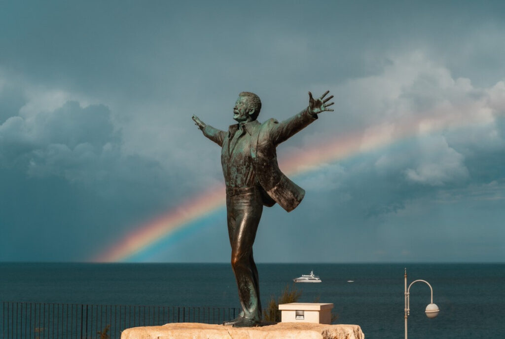 Domenico Modugno mit Regenbogen im Hintergrund.