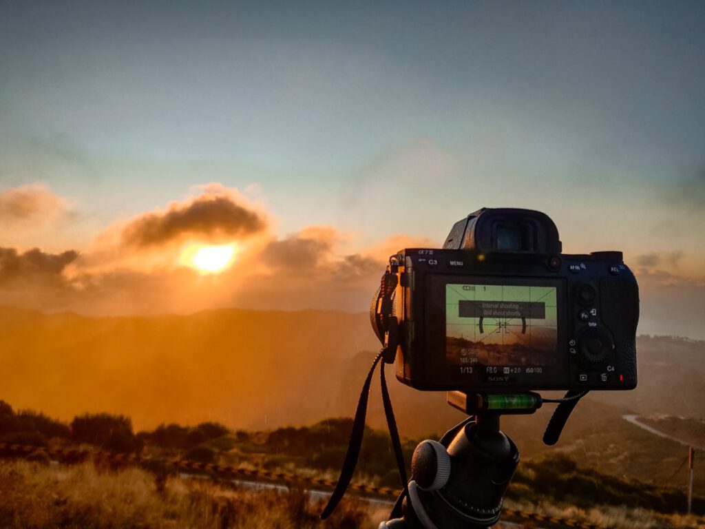 Kamera und Stativ auf dem gerade ein Foto eines Sonnenuntergangs geschossen wird