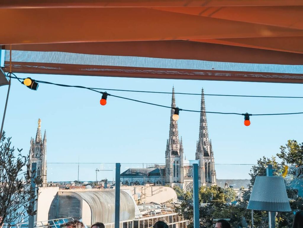 Rooftopbar mit Lichterketten und Ausblick auf die Kathedrale von Bordeaux