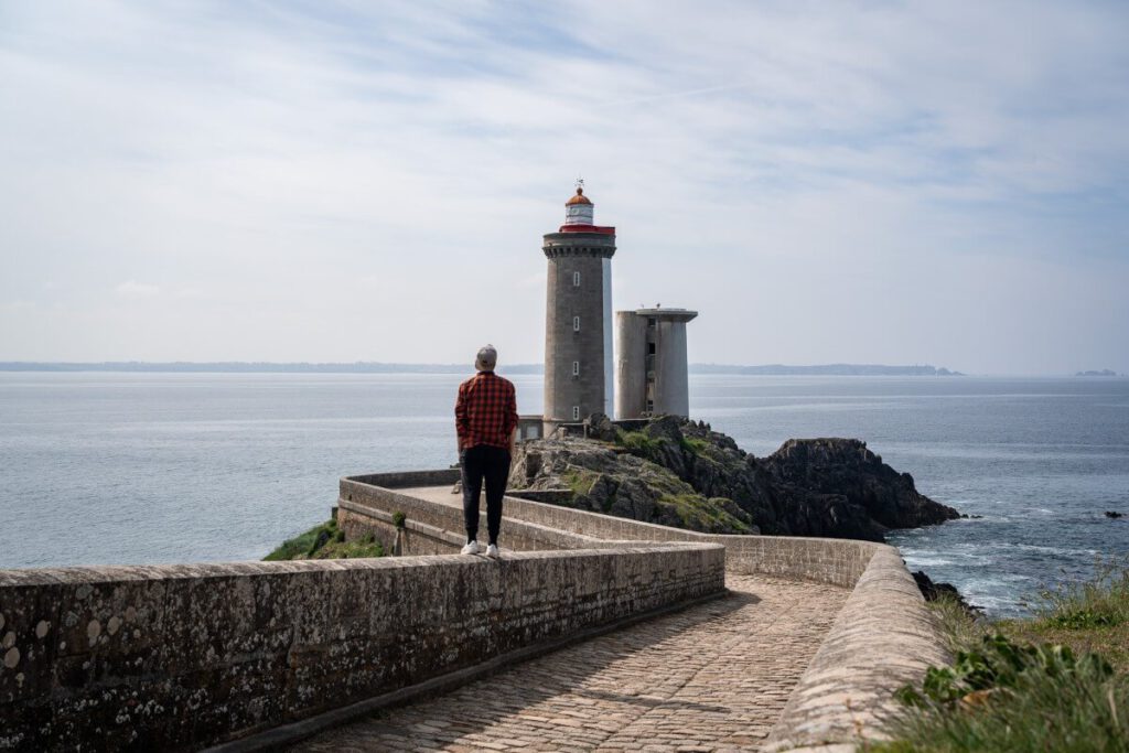 Mann steht auf Mauer vorm Phare du Petit Minou.