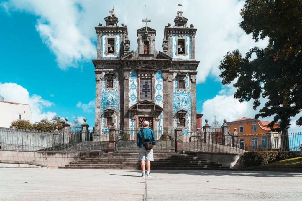 Ein Reisdender steht vor der Kirche Igreja de Santo Ildefonso