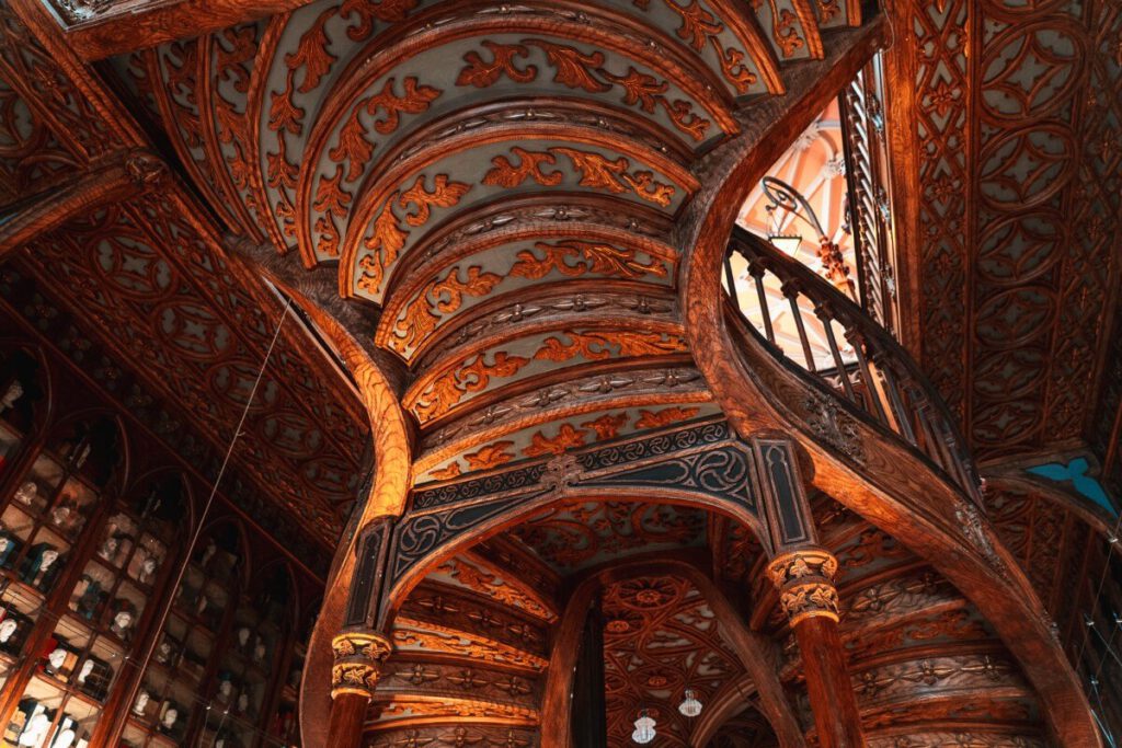 kunstvoll gestaltete, geschwungene Holztreppe mit rotem Teppich in der Bücherei Lello in Porto