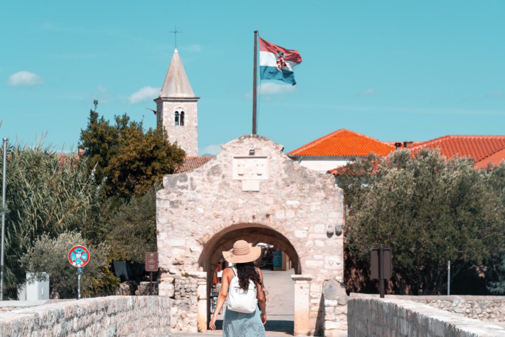 eine Touristin läuft durch das Stadttor von Nin in Kroatien