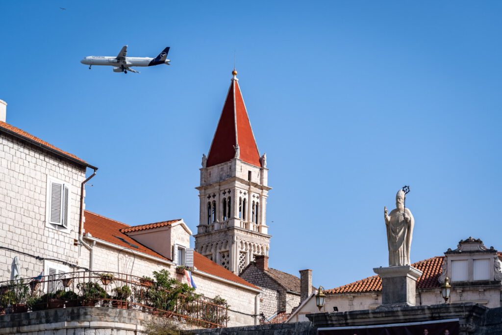 Ein Flugzeug fliegt über die Dächer der kroatischen Hafenstadt Trogir