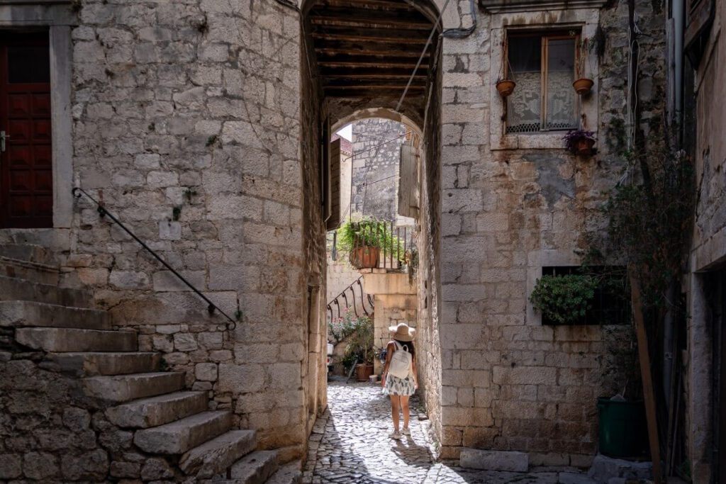 Eine Frau läuft durch eine Altstadt-Gasse in Trogir