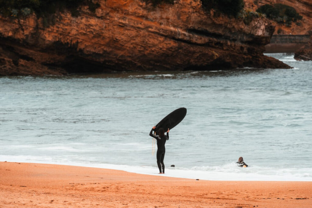 Ein Surfer am Strand hebt sein Surfbrett