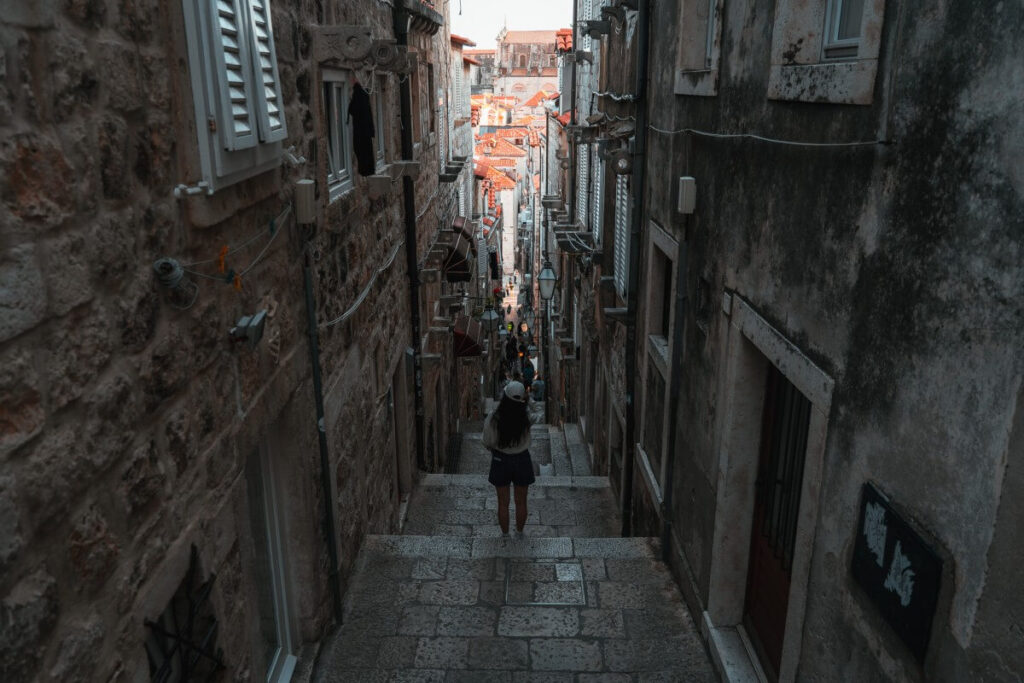 Frau steht auf einer Treppe in der Altstadt von Dubrovnik.