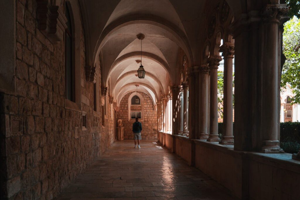 Mann läuft durch den Kreuzgang des Dominikanerklostess in Dubrovnik