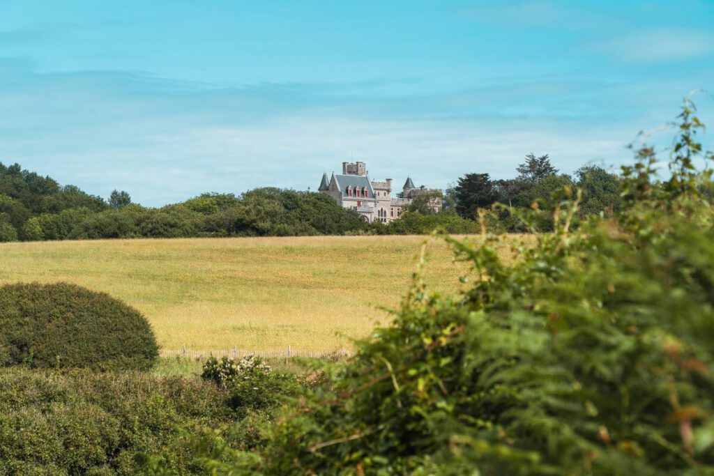 Schloss Abbadie auf einem Berg über einer Wiese
