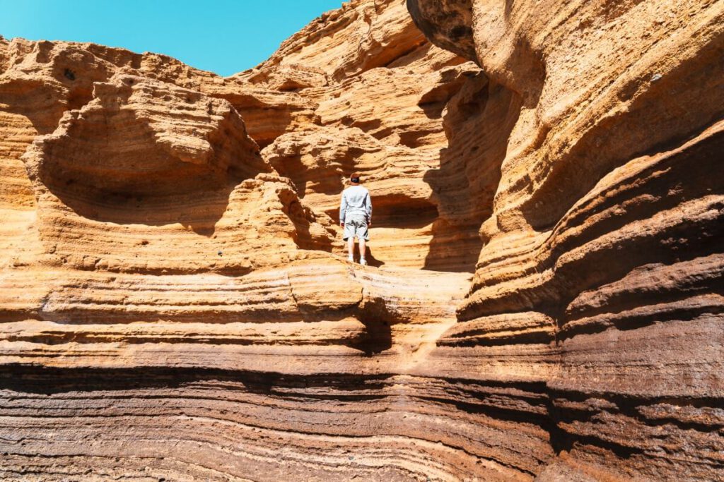 Mann steht auf einem Felsvorsprung an Playa Amarilla