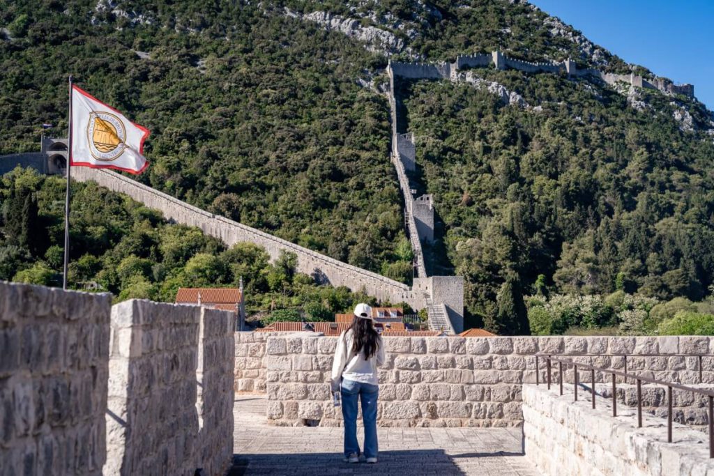 Frau steht auf der Festung von Ston und blickt auf die Stadtmauer